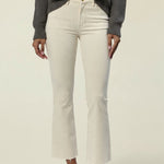 A model wearing off-white cropped flare jeans, a dark gray ribbed knit sweater, and brown leather flats, shown from the chest down against a plain light beige studio background.