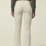 A person shown from the back wearing off-white flared jeans, a dark gray long-sleeve top, and brown flat shoes against a plain light beige studio background.
