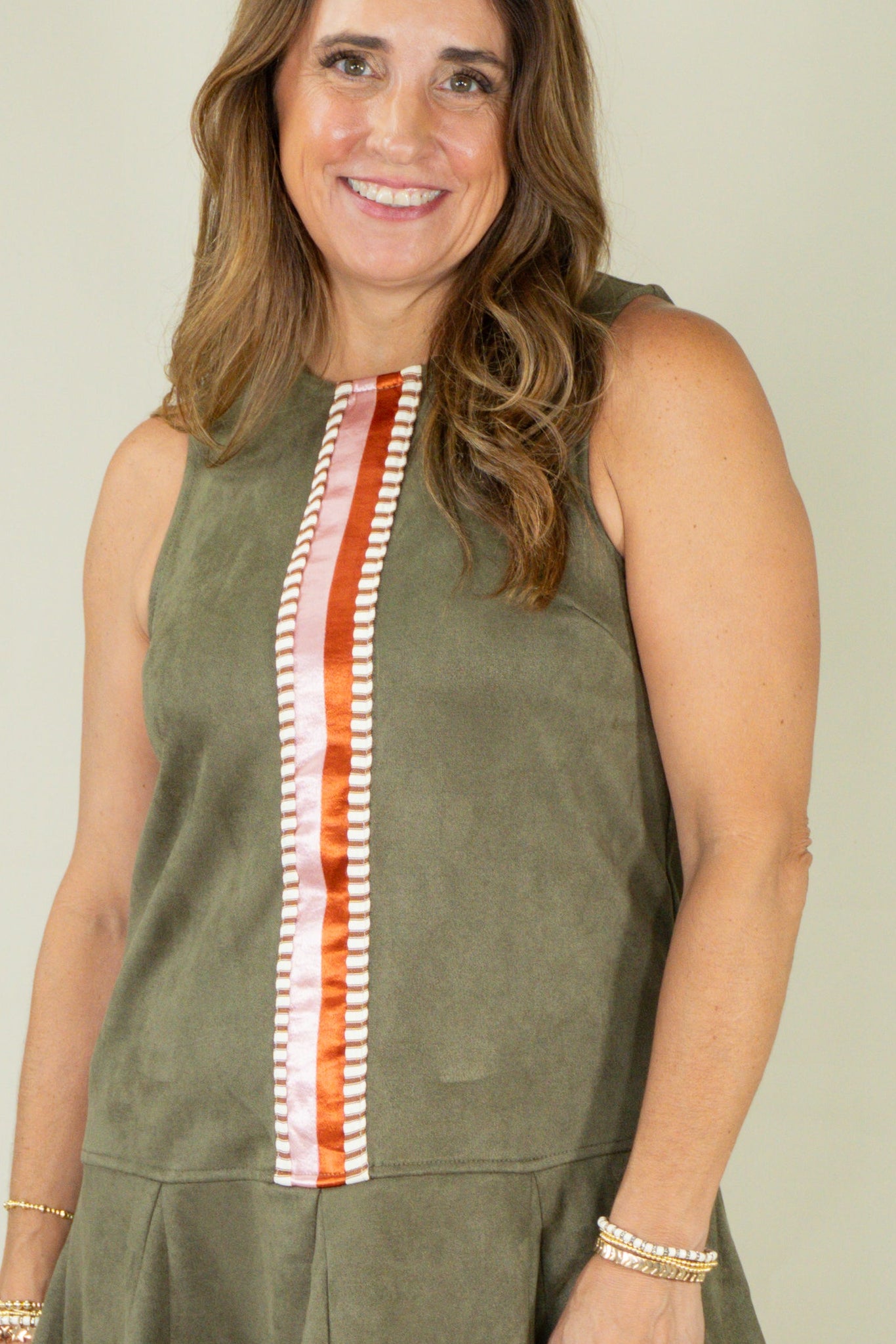 Woman wearing olive suede racing stripe dress with tan wedges