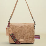 Beige handbag with floral patterns and a colorful strap on a white background