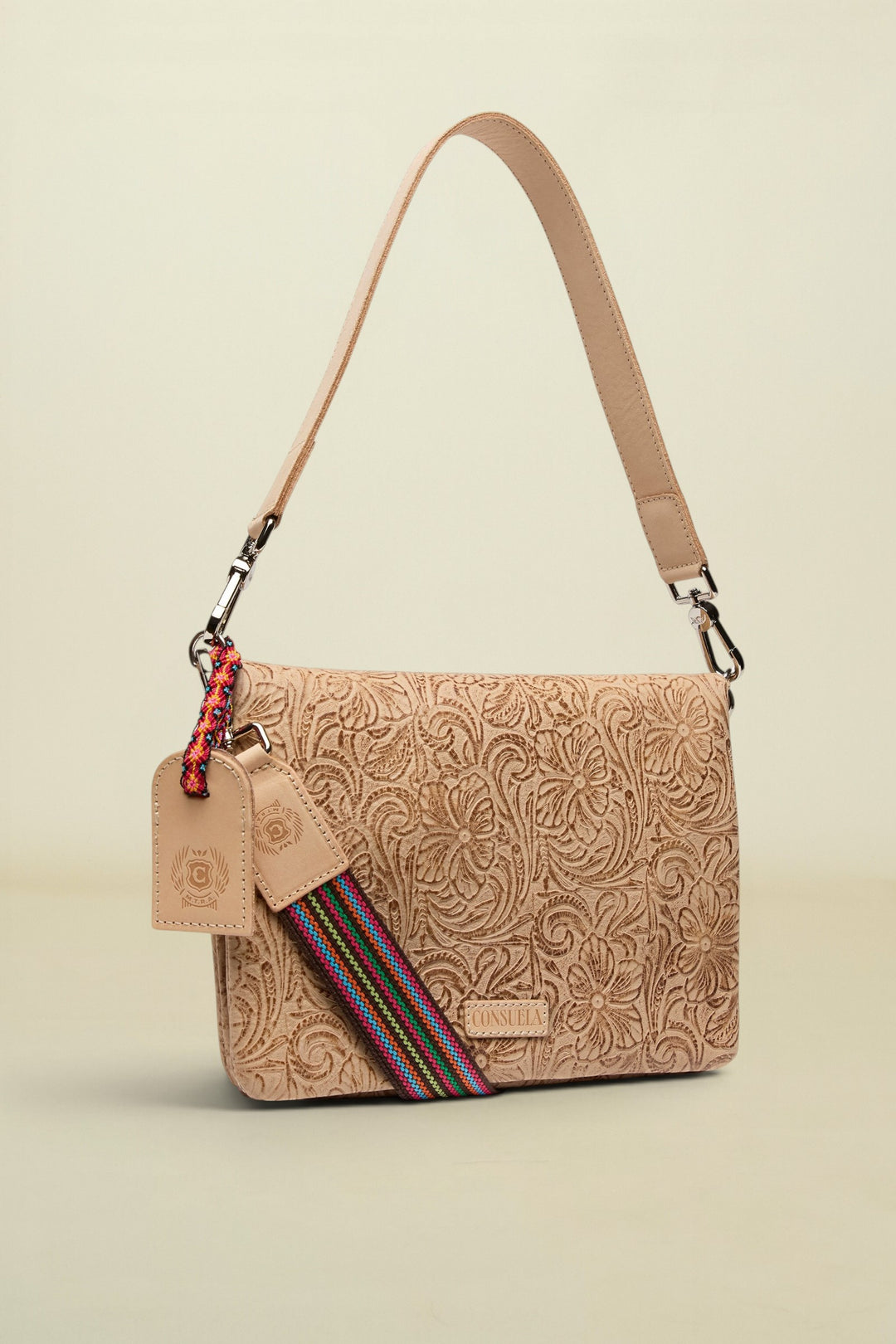 Beige patterned handbag with a strap and tag on a white background