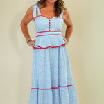 Woman wearing a light blue dress with red accents on a beige background
