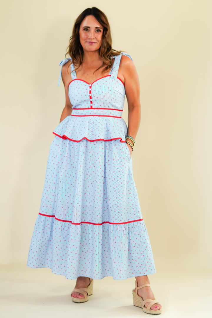 Woman wearing a light blue dress with red accents on a beige background