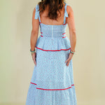 Woman wearing a light blue dress with red trim on a beige background