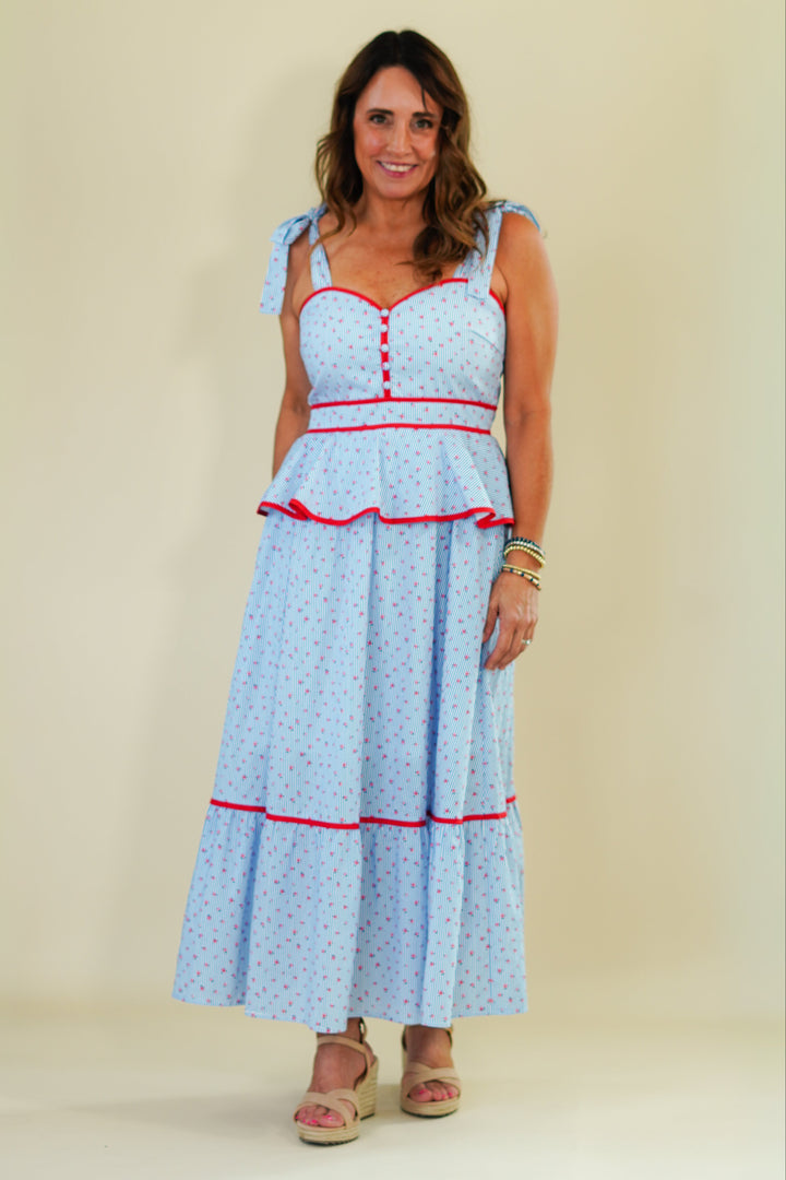 Woman wearing a light blue dress with red accents on a beige background