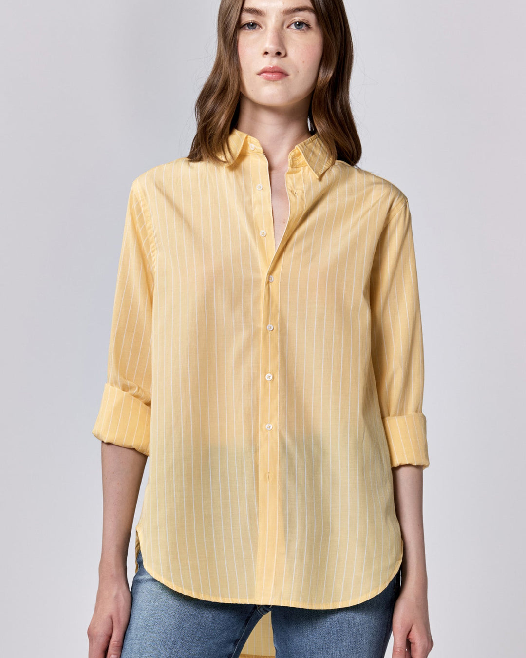 A woman wearing a long sleeve yellow striped button-down shirt with a collar