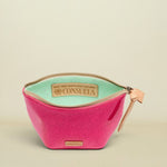 Pink cosmetic bag with green interior and Consuela branding on a white background