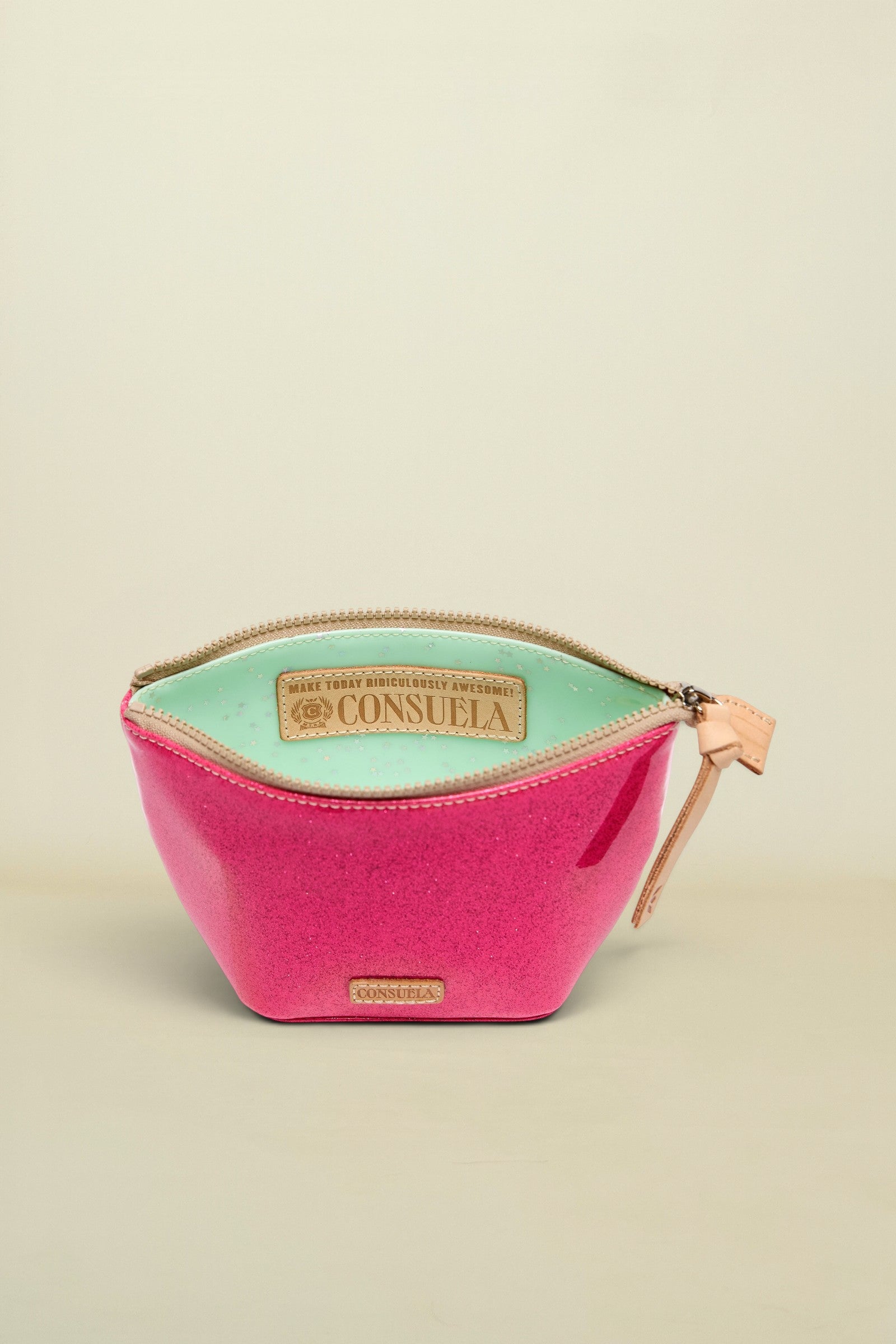 Pink cosmetic bag with green interior and Consuela branding on a white background