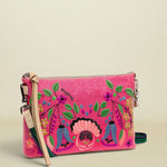 Pink clutch with colorful floral and figure design on a white background