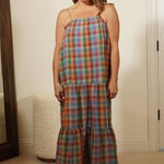 Person wearing a plaid dress standing in front of a mirror.