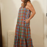 Woman in a plaid dress standing in front of a mirror in a room with white cabinets.