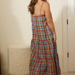 Woman in a plaid dress standing in front of a mirror in a room with white cabinets.