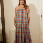Woman wearing a plaid dress standing in front of a mirror in a room.