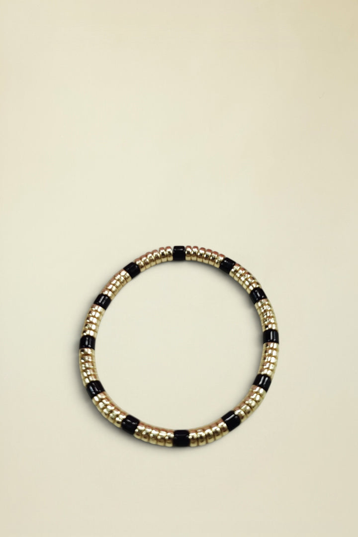 Bracelet with gold and black beads on a white background