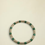 Bracelet with green and gold beads on a white background