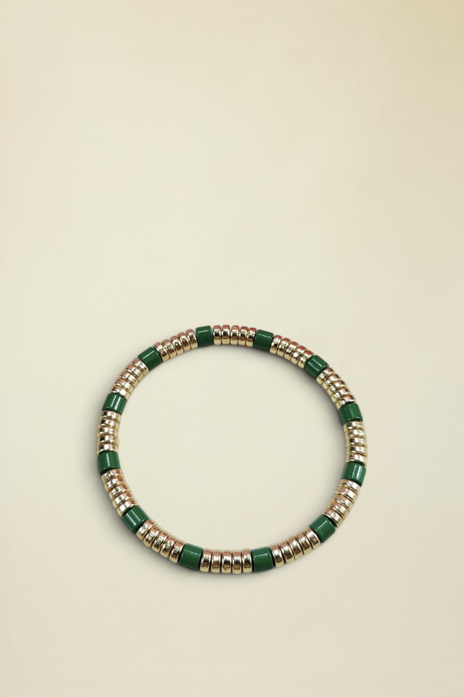 Bracelet with green and gold beads on a white background