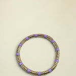 Bracelet with gold and purple beads on a light gray background