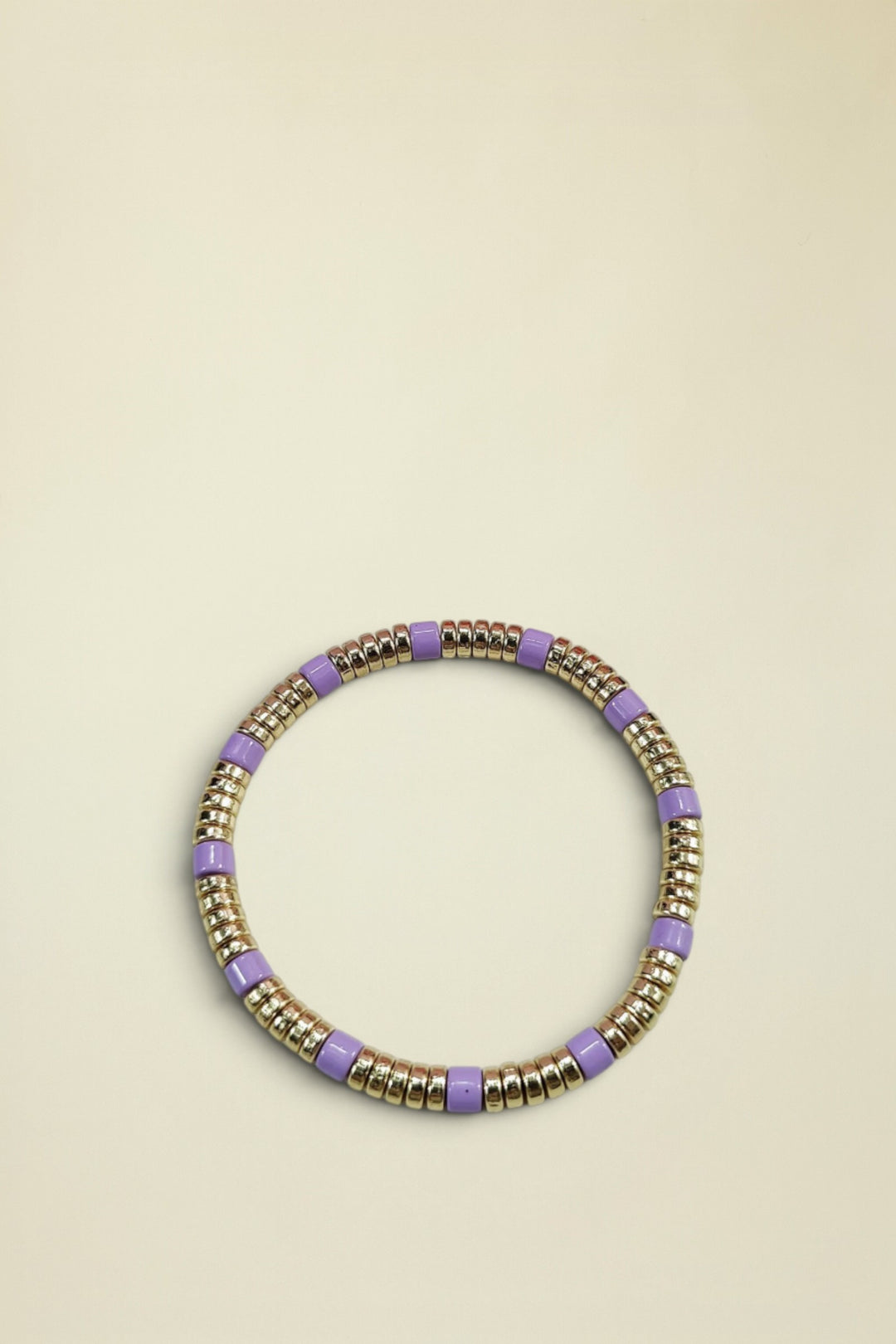 Bracelet with gold and purple beads on a light gray background