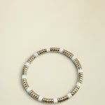 Bracelet with gold and white beads on a light gray background