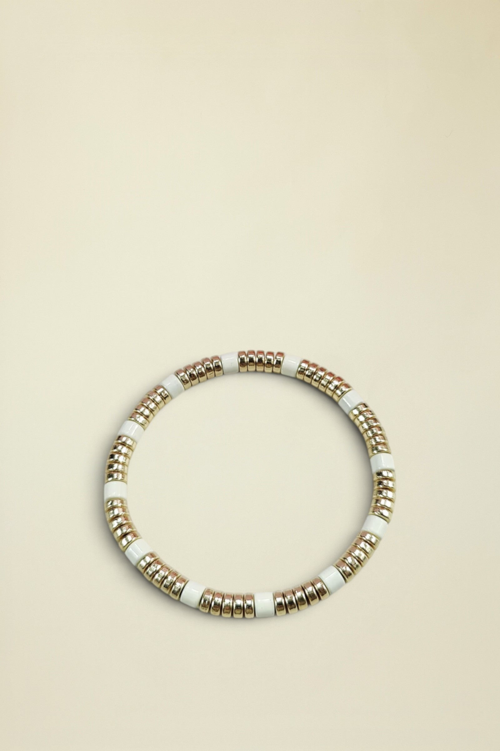 Bracelet with gold and white beads on a light gray background
