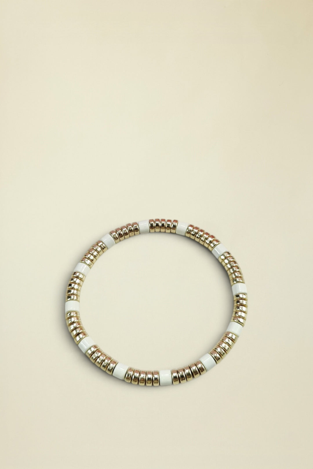 Bracelet with gold and white beads on a light gray background