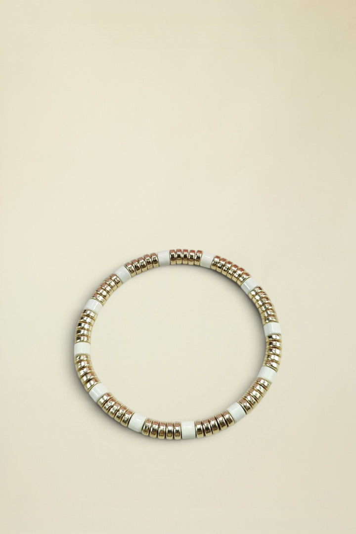 Bracelet with gold and white beads on a light gray background