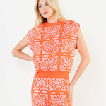 Woman wearing an orange and white patterned jumpsuit on a white background