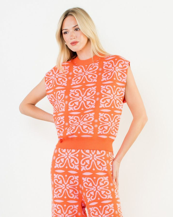 Woman wearing an orange and white patterned jumpsuit on a white background