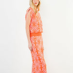 Woman wearing an orange and white patterned dress on a white background