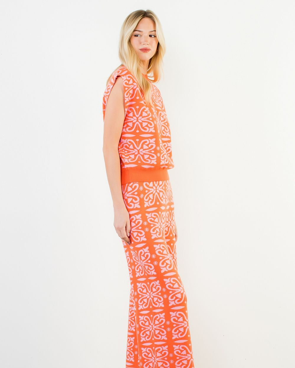 Woman wearing an orange and white patterned dress on a white background