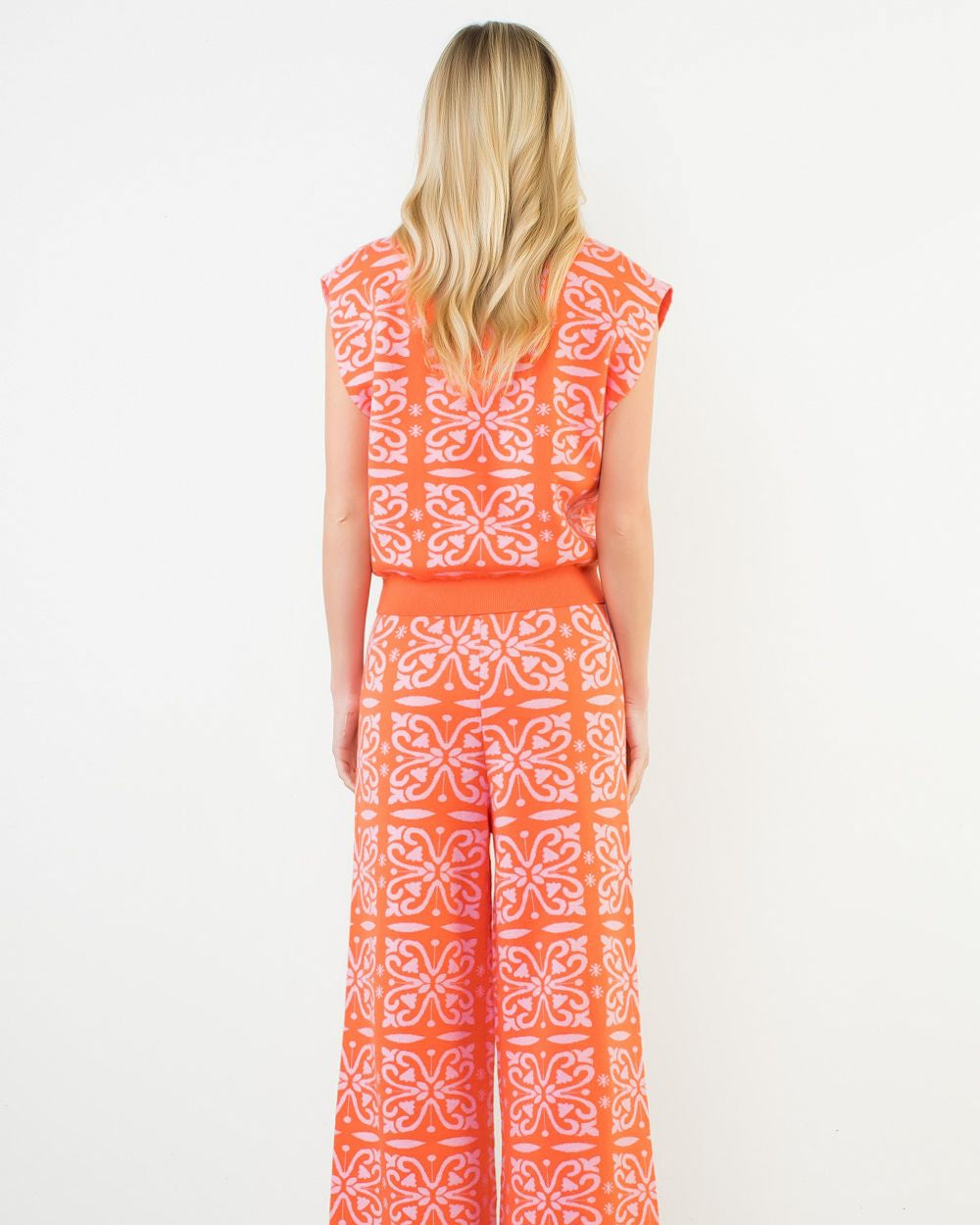 Woman wearing an orange and white patterned dress on a white background
