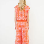Woman wearing an orange and white patterned dress on a white background