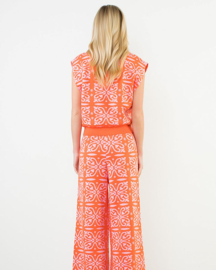 Woman wearing an orange and white patterned dress on a white background
