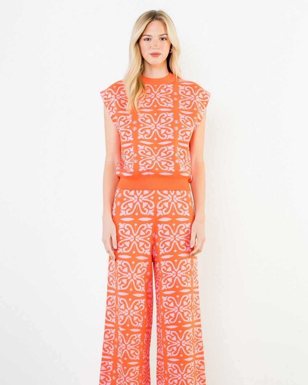 Woman wearing an orange and white patterned outfit on a white background