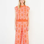 Woman wearing an orange and white patterned outfit on a white background