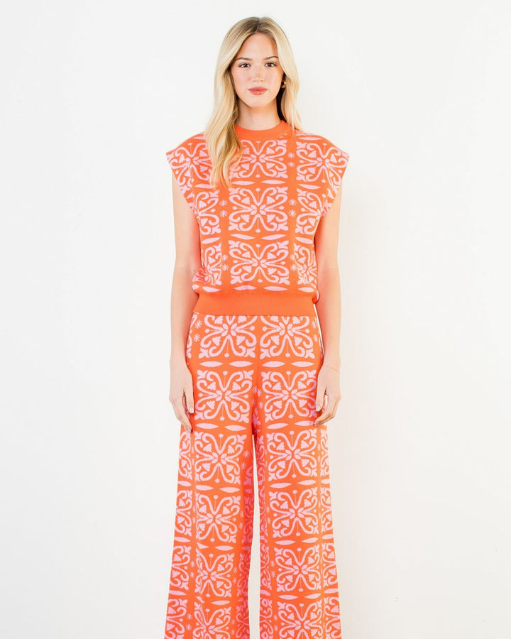 Woman wearing an orange and white patterned outfit on a white background