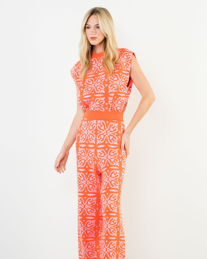Woman wearing a coral patterned jumpsuit on a white background