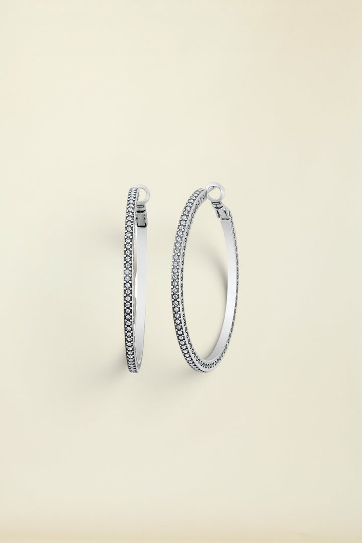 A pair of silver hoop earrings with fine crystal pave details, displayed against a white background.