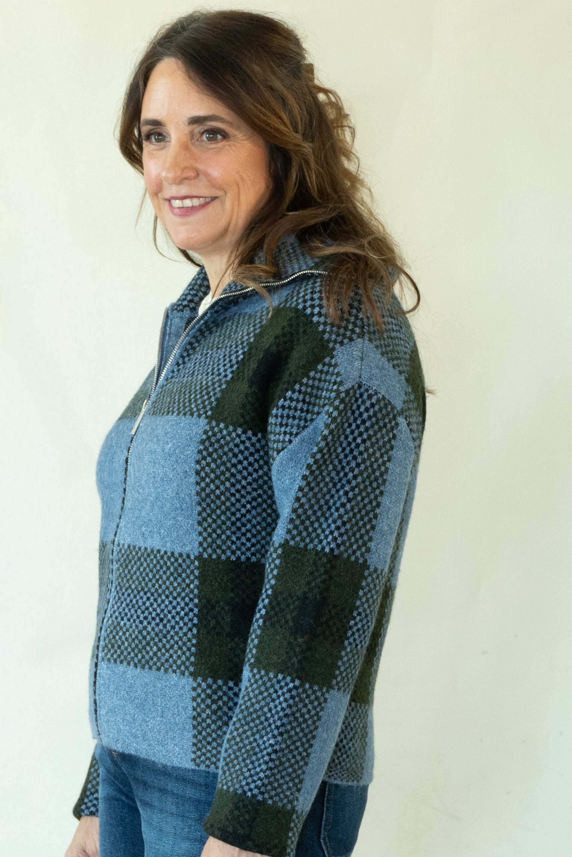 Woman wearing blue and green buffalo check zip front cardigan with dark jeans and ankle boots