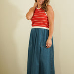 Woman wearing a red striped top and blue denim skirt against a plain background