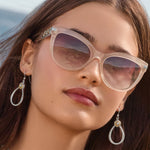 Close-up of a woman wearing sunglasses with a blurred beach background