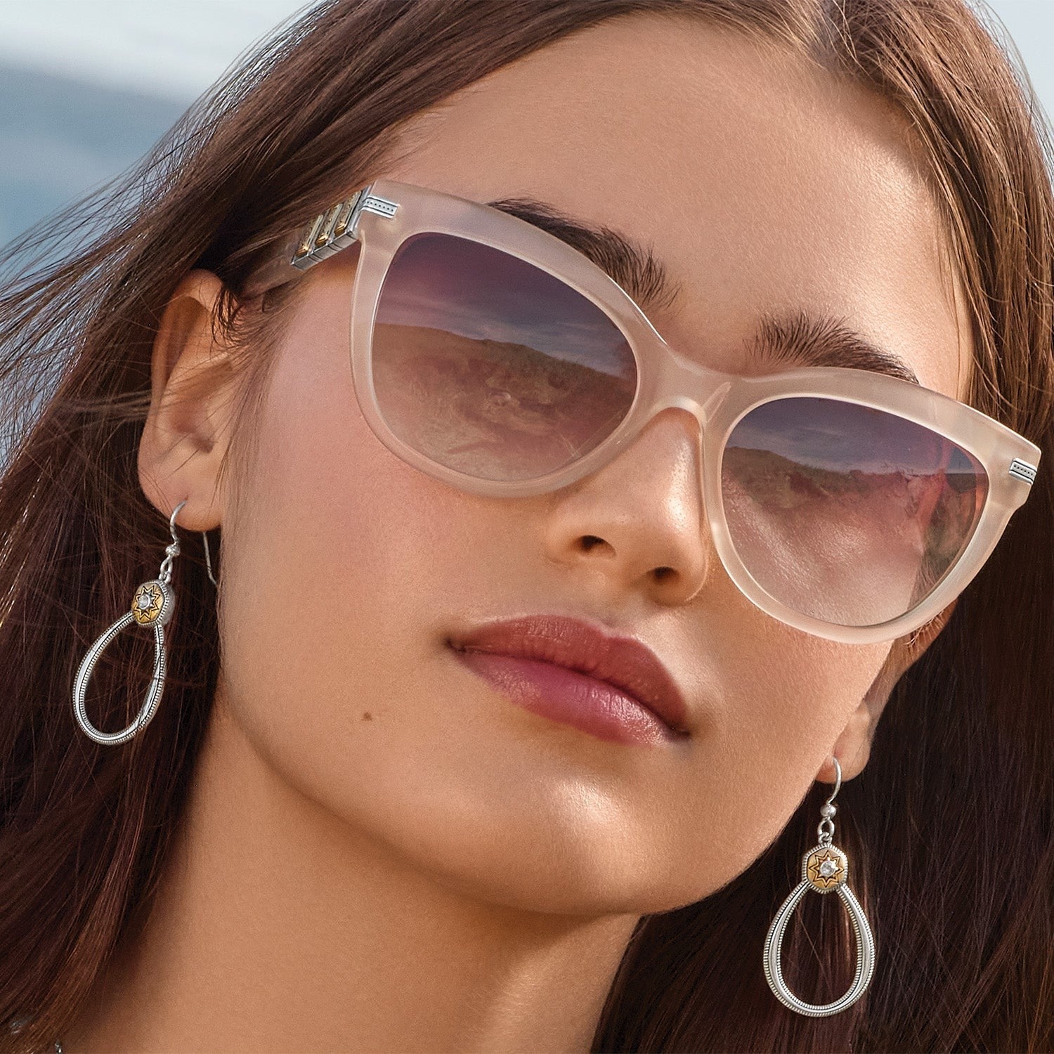 Close-up of a woman wearing sunglasses with a blurred beach background