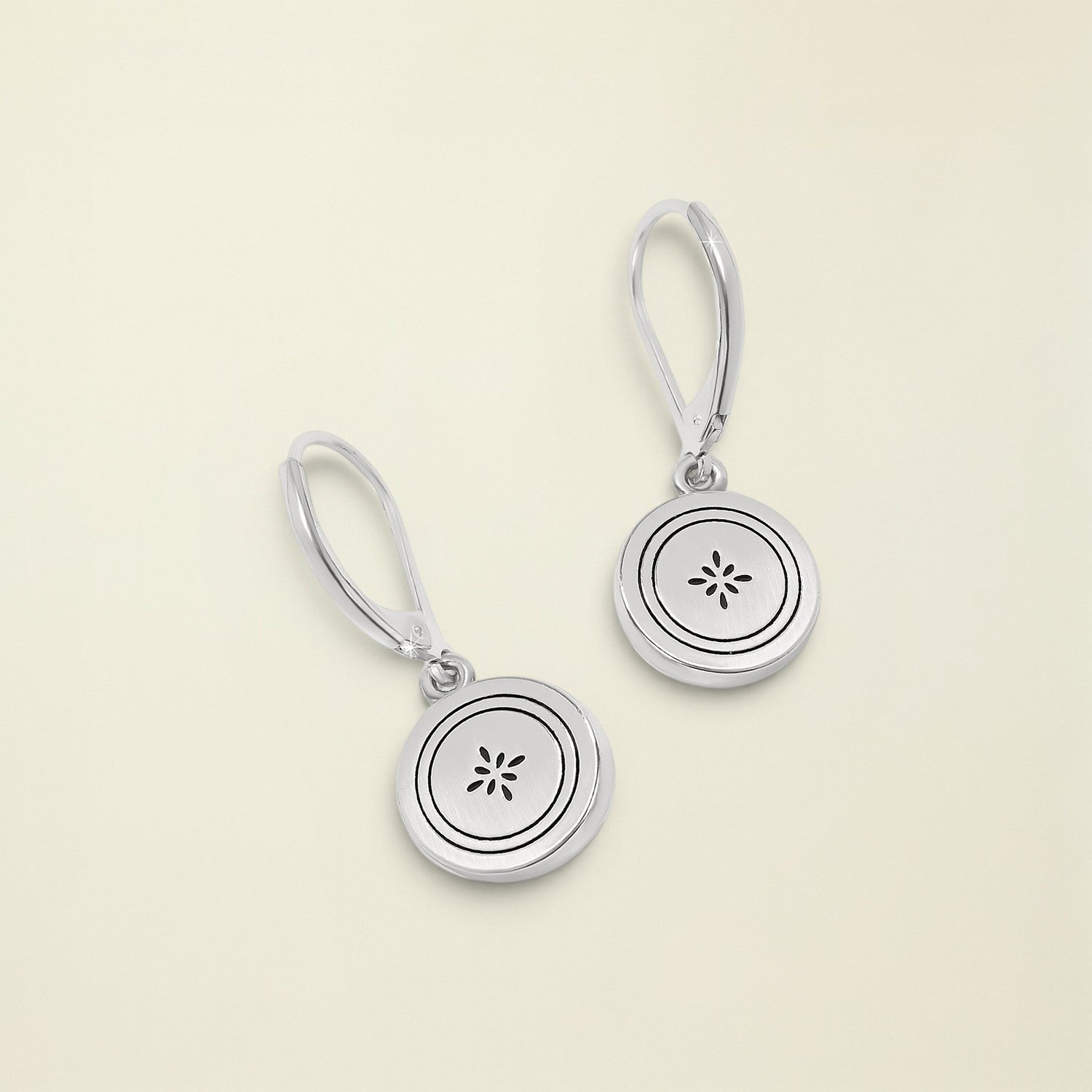 Silver earrings with circular designs on a white background