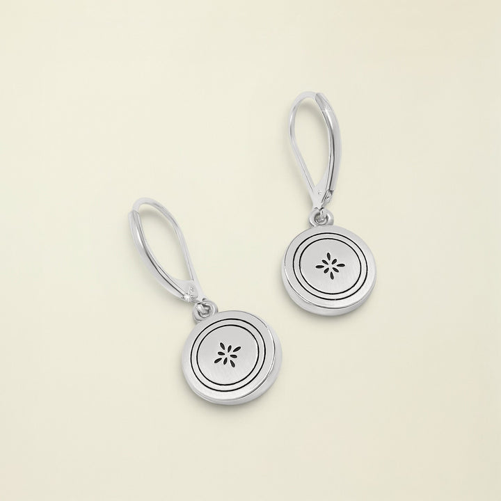 Silver earrings with circular designs on a white background