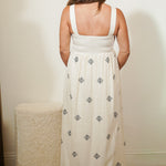 Woman wearing a white dress with black patterns in a minimal indoor setting