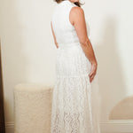 Woman wearing a white lace dress standing in a room with a neutral background
