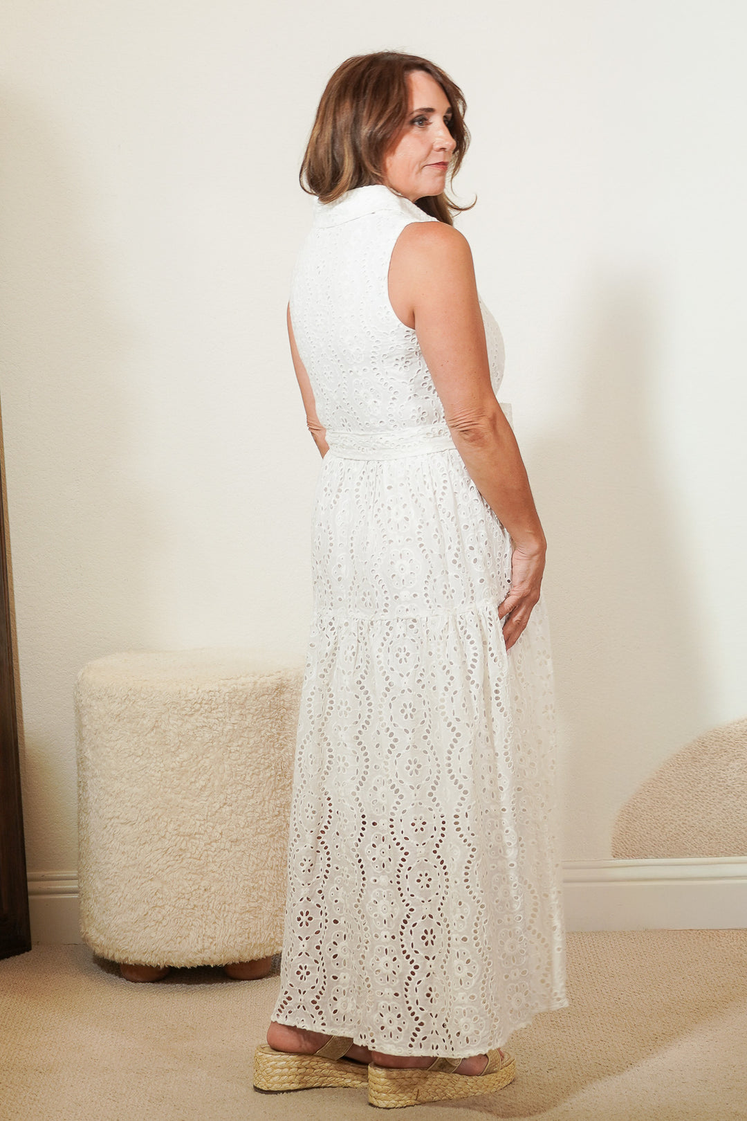 Woman wearing a white lace dress standing in a room with a neutral background