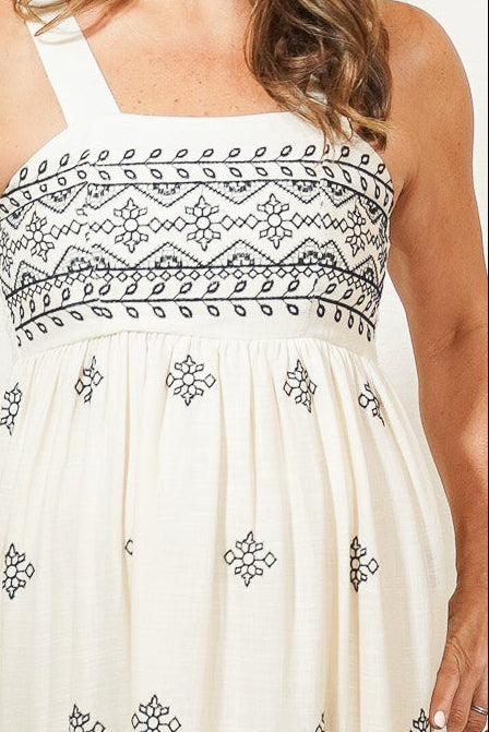 Woman wearing a white dress with black patterns in a room.