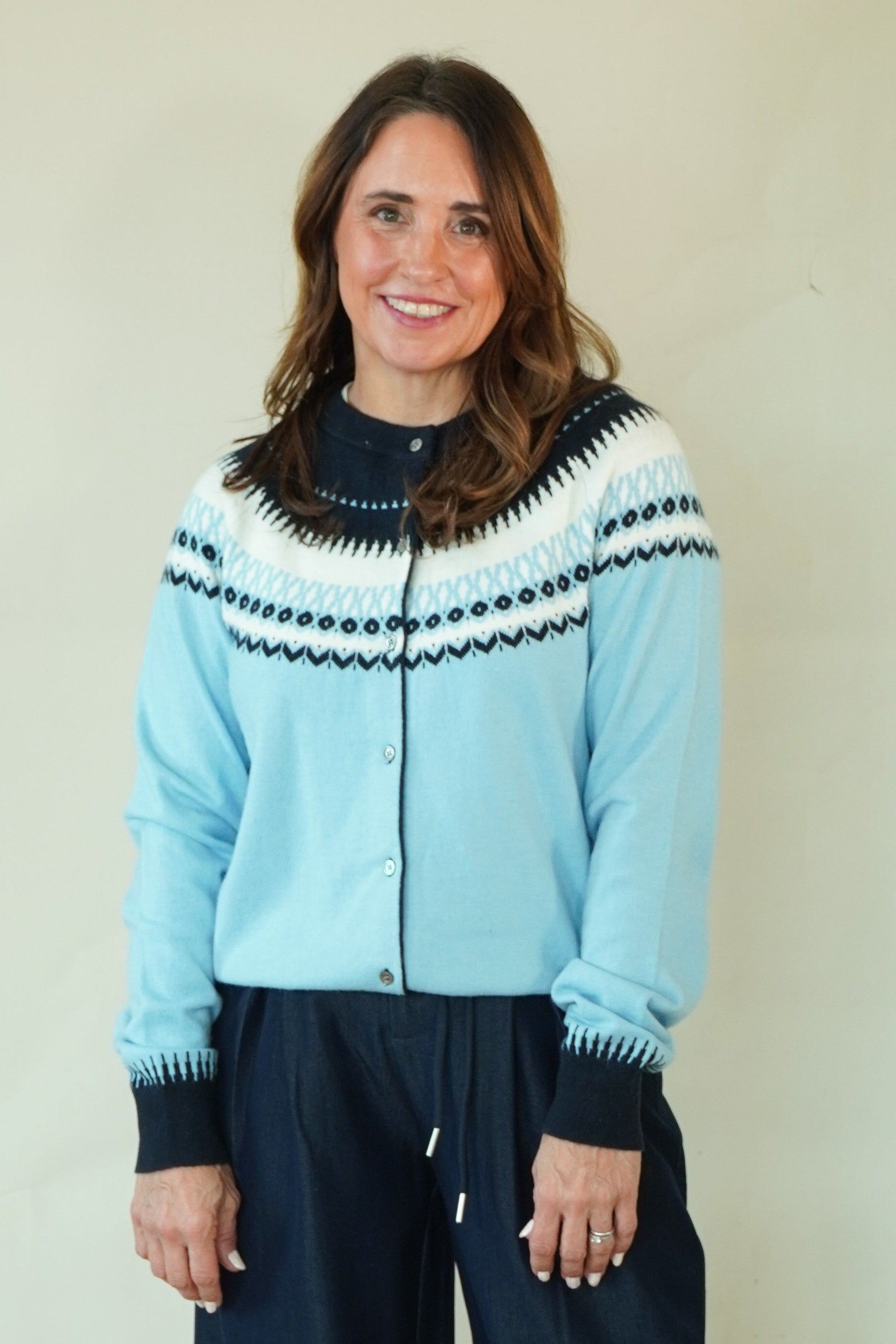 Woman wearing blue Fair Isle cardigan with navy trousers