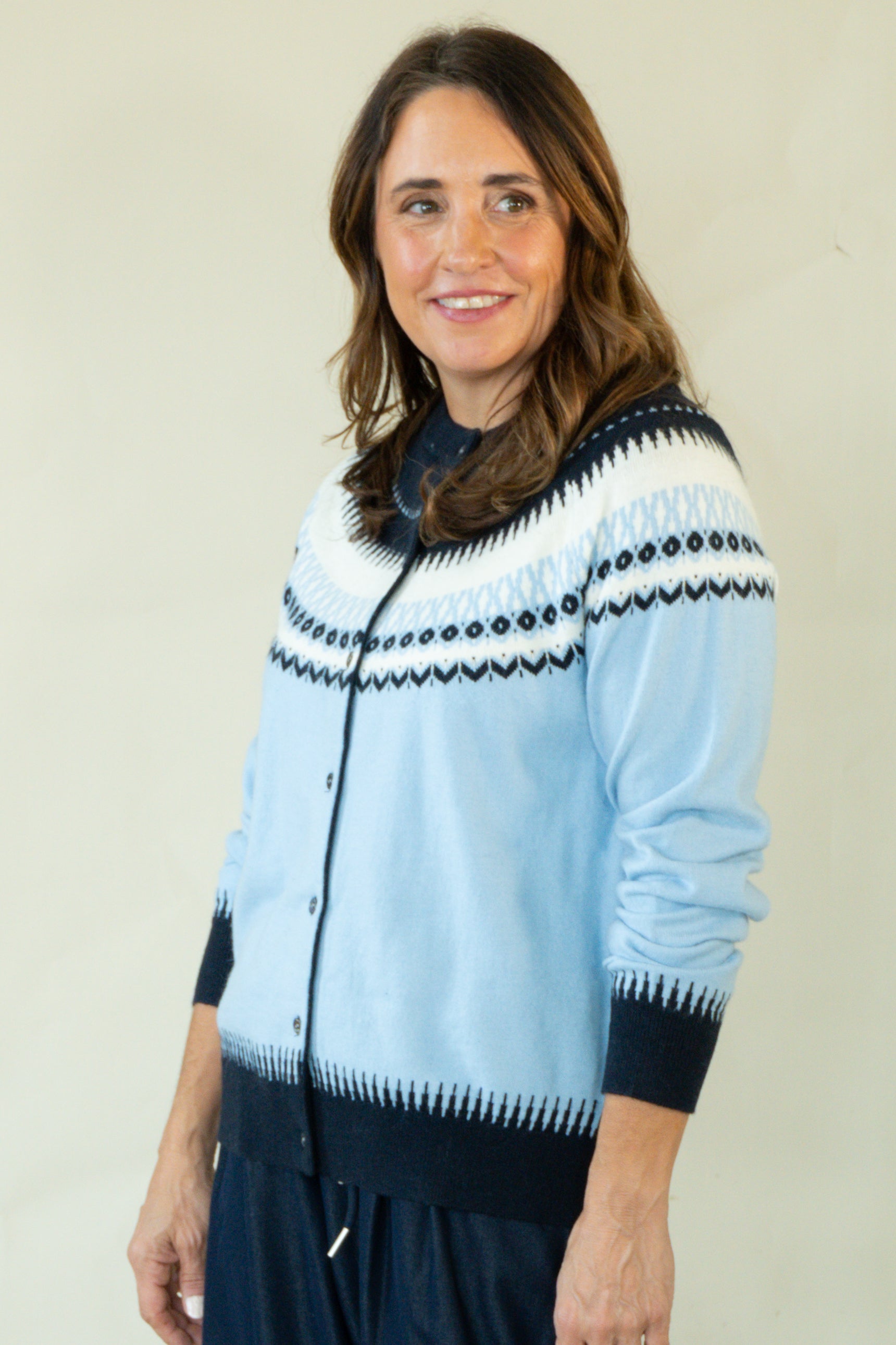 Woman wearing blue Fair Isle cardigan with navy trousers and Close-up of Fair Isle pattern yoke on blue cardigan